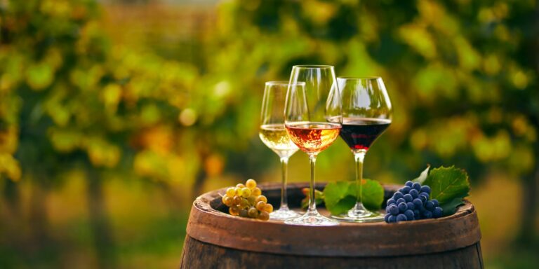 Three glasses with white, rose and red wine on a wooden barrel i